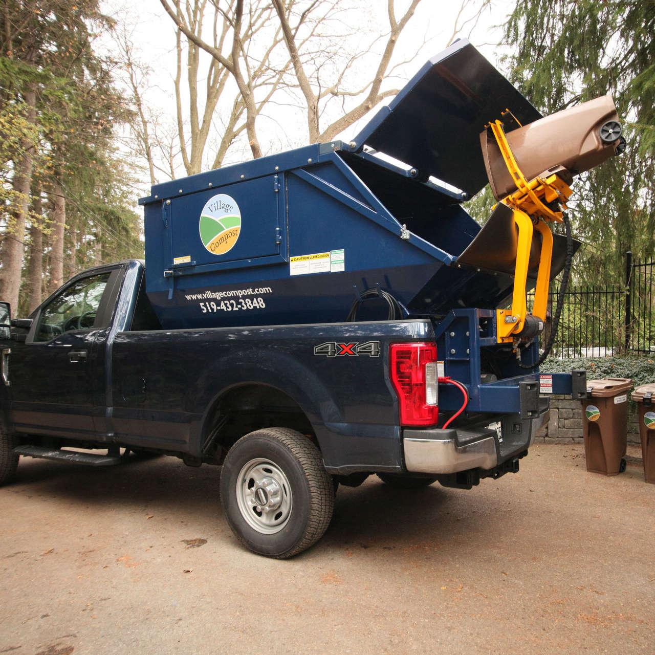 A Village Compost Limited compost pick-up truck collecting compost from a lifted bin - Village Compost - Compost Pick-Up Services & More - London, Ontario.
